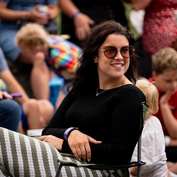 dynes yn gwisgo sbectol haul yn gwenu